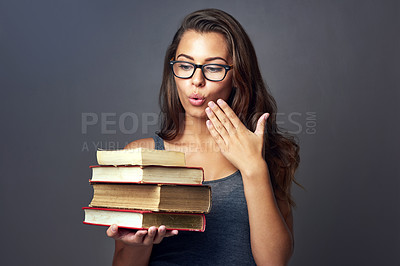 Buy stock photo Studio shot of a young woman looking shocked while holding a pile of books against a grey background