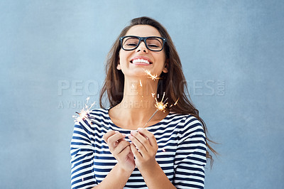 Buy stock photo Studio portrait of a beautiful young woman holding sparklers against a blue background