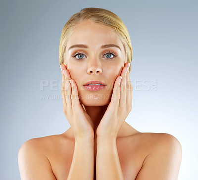 Buy stock photo Studio portrait of a beautiful young blonde woman posing against a blue background