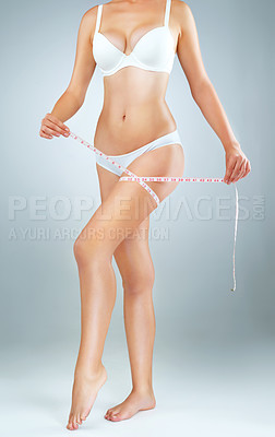 Buy stock photo Leg, tape measure and woman in studio for weight loss, healthy diet or fitness with gray background. Underwear, wellness and hands of model for results in exercise, transformation or body goals