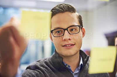 Buy stock photo Cropped shot of a young businessman brainstorming on a glass wall in an office