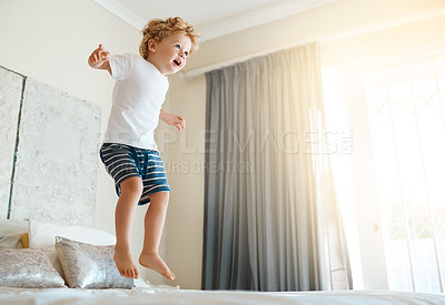Buy stock photo Shot of an adorable little boy jumping on the bed at home