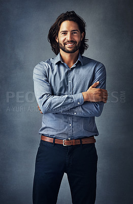 Buy stock photo Studio portrait of a handsome young man standing with his arms folded against a grey background