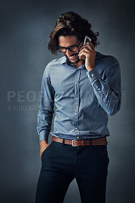 Buy stock photo Studio shot of a handsome young man talking on his cellphone while standing against a grey background