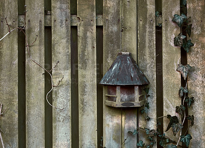 Buy stock photo An old creepy wooden fence on a summer day in a remote village. A spooky barricade on a Halloween morning with a chilling feel. An eerie barrier with a strange antique rustic birdhouse on it