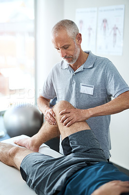 Buy stock photo Cropped shot of a handsome mature male physiotherapist treating an unrecognizable patient
