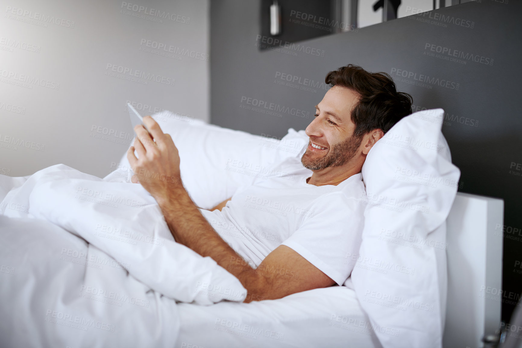 Buy stock photo Home, happy and man with tablet in bed for web search, communication and reading email in morning. Media, app and male person with tech in house for digital news site, information and connectivity