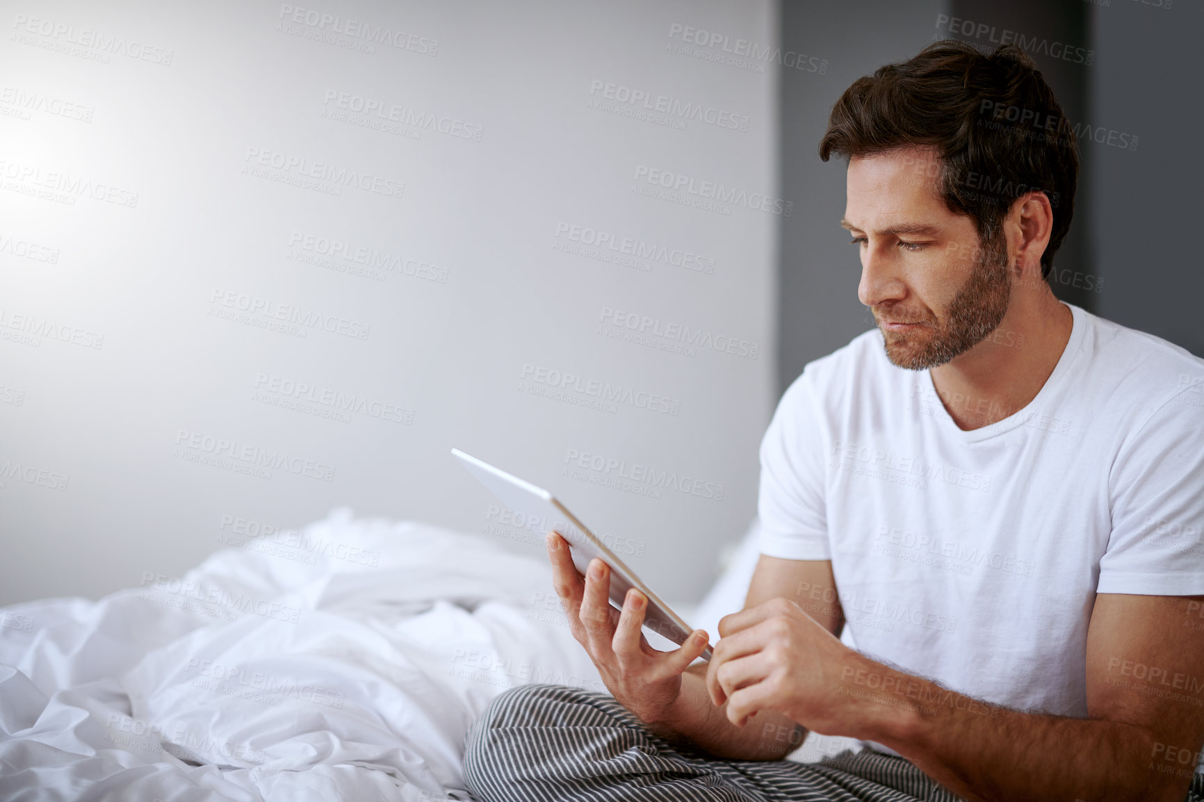 Buy stock photo Home, internet and man with tablet in bedroom for online, connectivity and reading email in morning. Relax, media and male person with technology in house for message, communication and notification