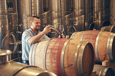 Buy stock photo Cropped shot of a handsome young male sommelier pouring a glass of wine right out the barrel