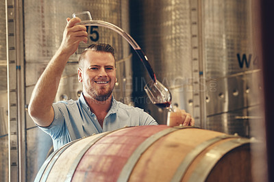 Buy stock photo Cropped portrait of a handsome young male sommelier pouring a glass of wine right out the barrel