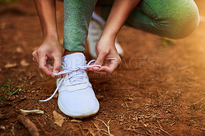 Buy stock photo Shot of a sporty young woman tying her shoelaces before a run