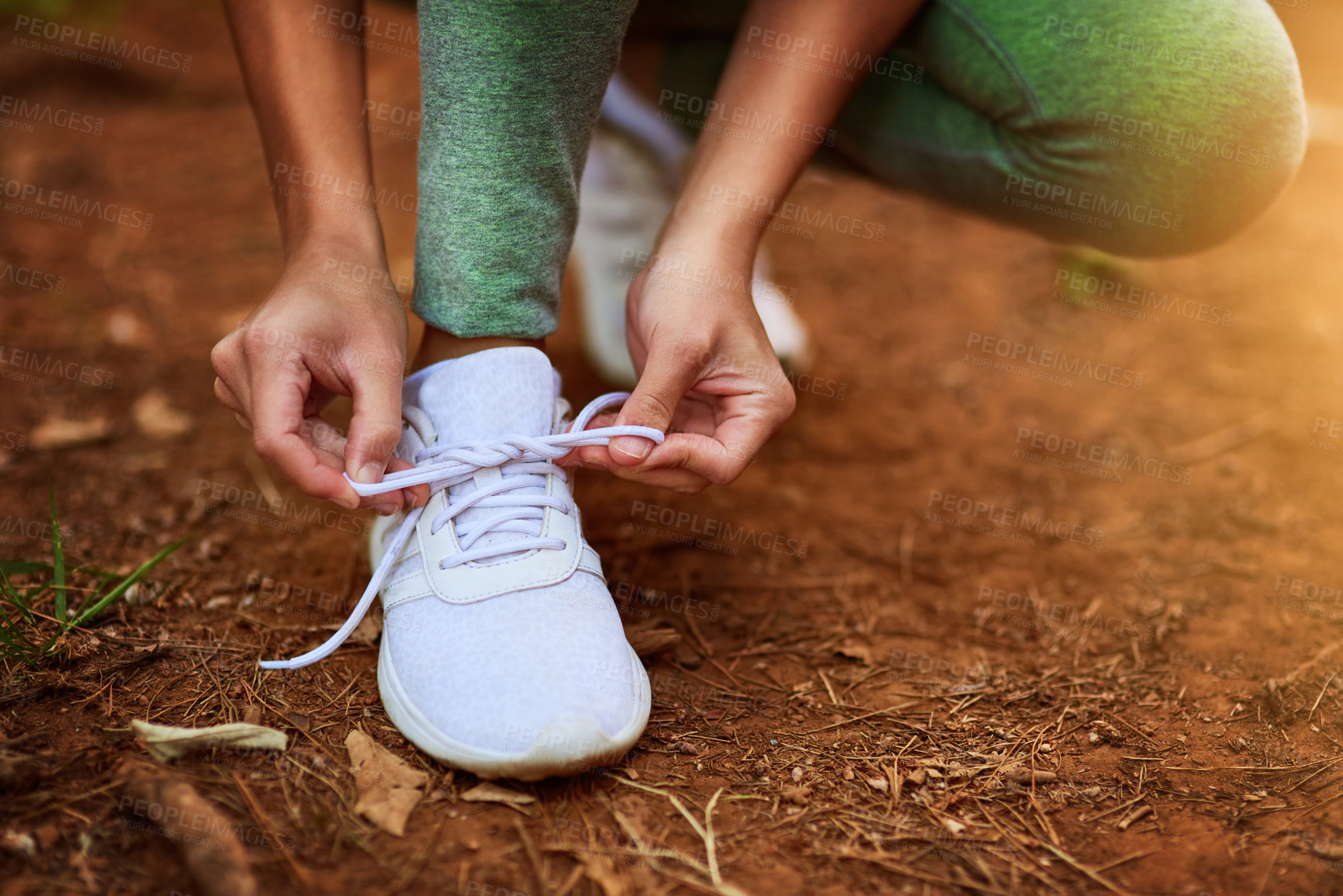 Buy stock photo Shot of a sporty young woman tying her shoelaces before a run