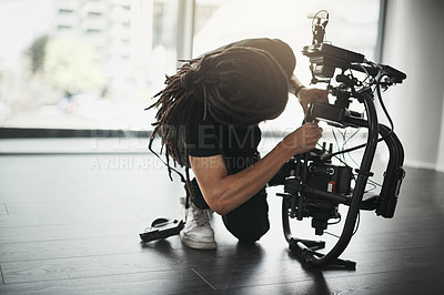 Buy stock photo Behind the scenes shot of a videographer working on a state of the art video camera inside of a studio during the day