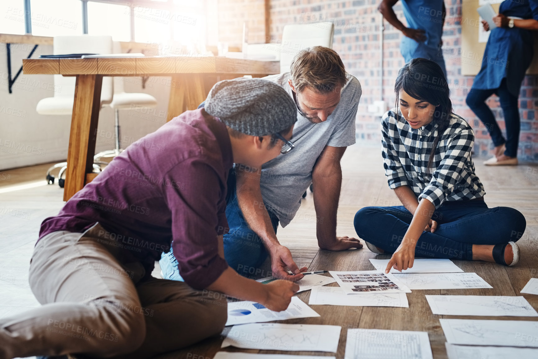 Buy stock photo Shot of a group of businesspeople brainstorming on the floor in an office