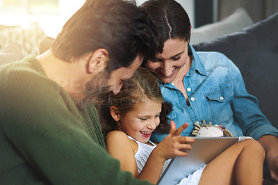 Buy stock photo Cropped shot of a young family using a tablet and chilling on the sofa together at home