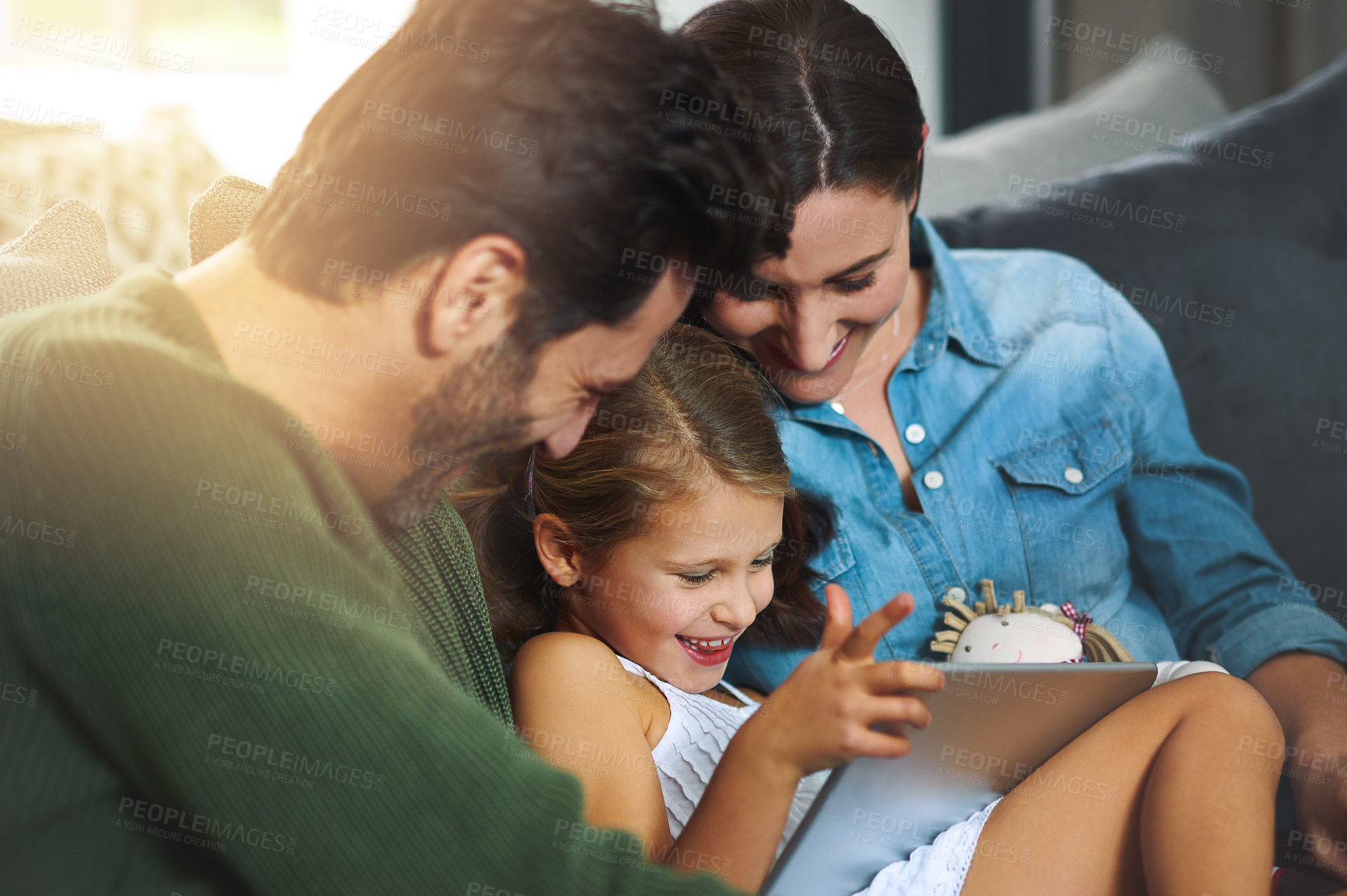 Buy stock photo Cropped shot of a young family using a tablet and chilling on the sofa together at home