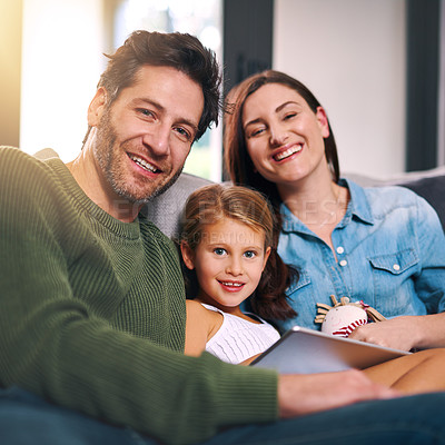 Buy stock photo Cropped shot of a young family using a tablet and chilling on the sofa together at home