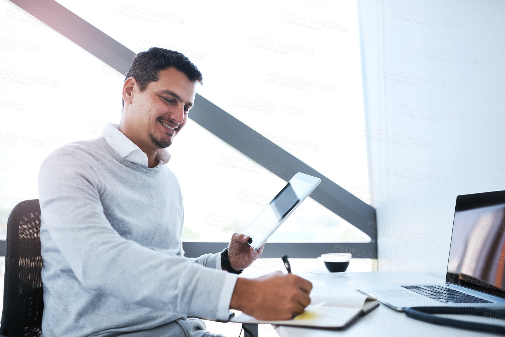 Buy stock photo Shot of a young businessman working on a digital tablet in an office