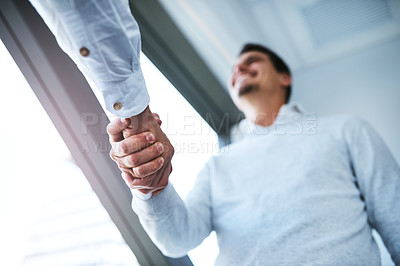 Buy stock photo Low angle shot of two businessmen shaking hands in an office
