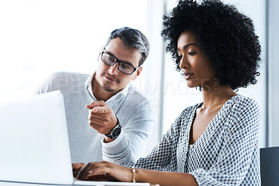 Buy stock photo Shot of two businesspeople working together on a laptop in an office