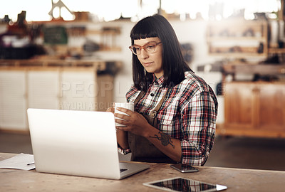 Buy stock photo Cropped shot of an attractive young woman working on her laptop while sitting in her creative workshop