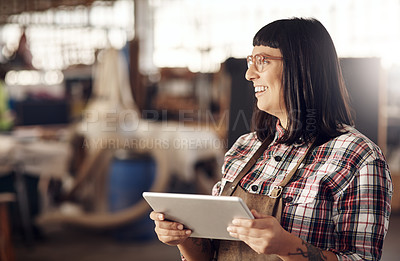 Buy stock photo Cropped shot of an attractive young woman looking thoughtful while working on her tablet in her creative workshop