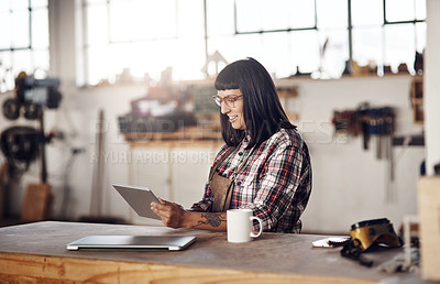 Buy stock photo Cropped shot of an attractive young woman working on her tablet while sitting in her creative workshop