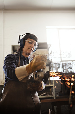 Buy stock photo Cropped shot of an attractive young female artisan using an angle grinder in her workshop