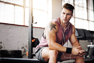 Buy stock photo Cropped shot of a handsome young man taking a break during his workout at the gym