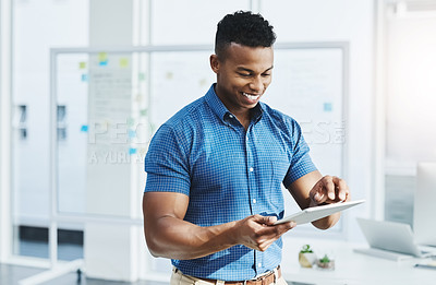 Buy stock photo Shot of a young businessman using a digital tablet in an office