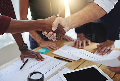 Buy stock photo Cropped shot of two unrecognizable creative employees shaking hands while working in a modern office