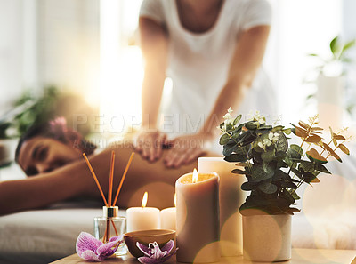 Buy stock photo Shot of spa essentials on a table with a woman getting a massage in the background