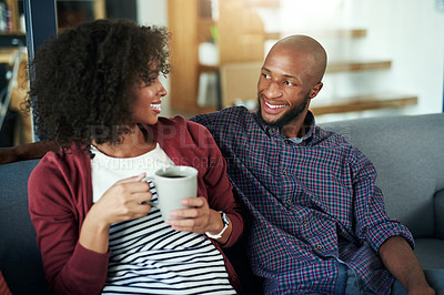 Buy stock photo Shot of a happy young couple enjoying a relaxing coffee break together on the sofa at home