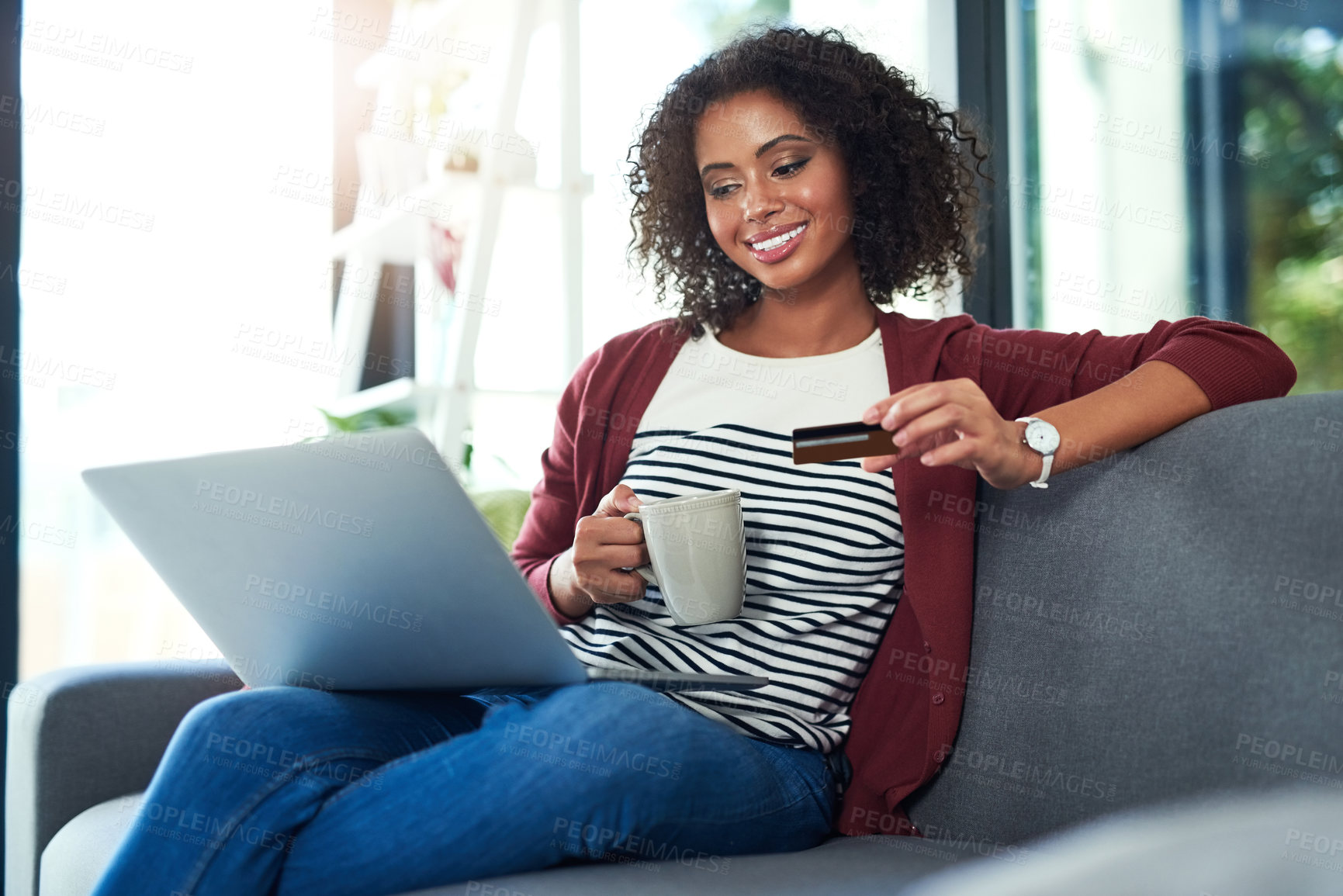 Buy stock photo Shot of a young woman using a laptop and credit card on the sofa at home