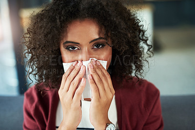 Buy stock photo Portrait of a young woman blowing her nose while sitting on the sofa at home