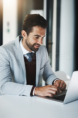 Buy stock photo Shot of a young businessman working on a laptop in an office