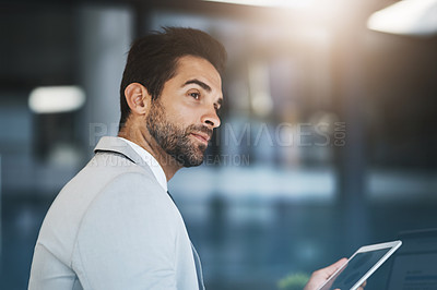 Buy stock photo Shot of a young businessman working on a digital tablet in an office