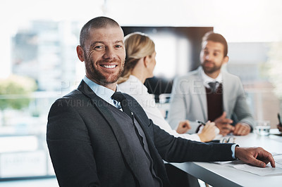 Buy stock photo Portrait of a mature businessman sitting in an office with his colleagues in the background