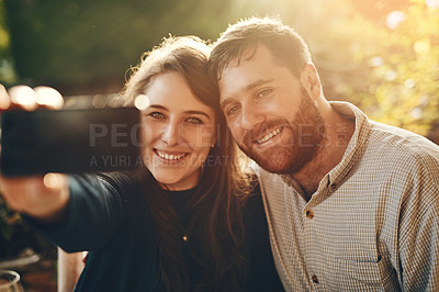Buy stock photo Happy, phone and couple love to take a selfie at an outdoor restaurant for a romantic date in spring. Relax, memory and young woman taking pictures with a young partner smiles on marriage anniversary