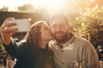 Buy stock photo Happy couple, selfie on a phone with a kiss for love, care and support while outdoor in garden with lens flare for summer. Man and woman together with smartphone for social media profile picture