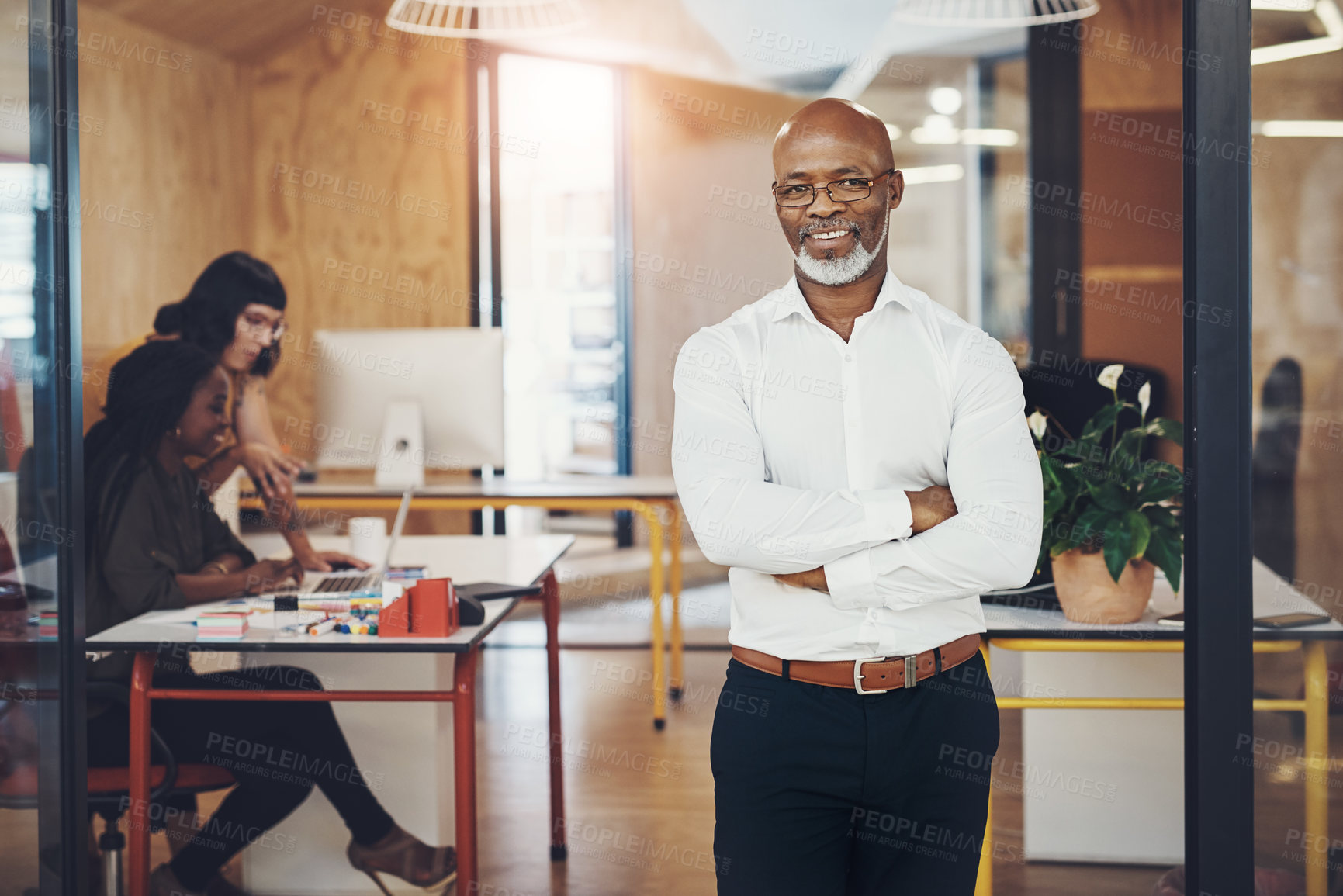 Buy stock photo Portrait of a mature businessman standing with his arms crossed in an office