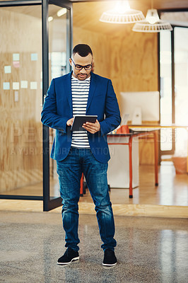 Buy stock photo Shot of a young businessman using a digital tablet at the office