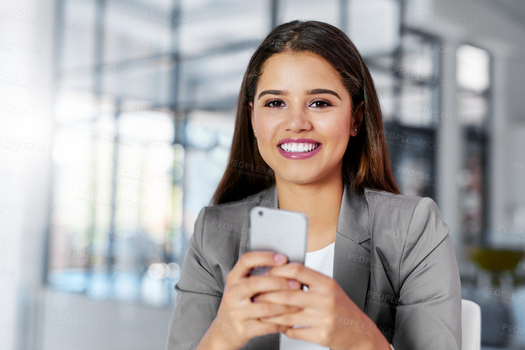 Buy stock photo Cropped portrait of a young businesswoman texting on a cellphone in an office
