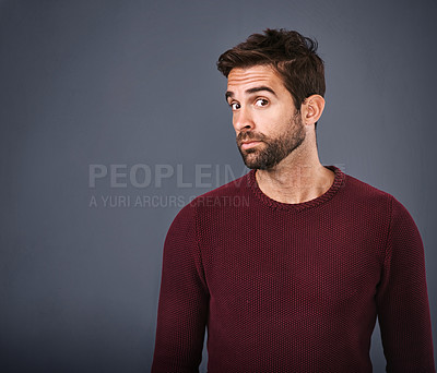Buy stock photo Studio shot of a handsome young man looking skeptical against a gray background