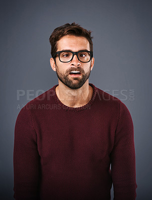 Buy stock photo Studio shot of a handsome young man pulling funny faces against a gray background