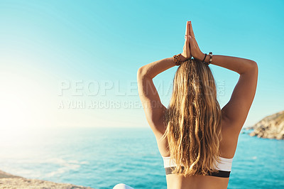 Buy stock photo Rearview shot of a young woman practicing yoga on the beach