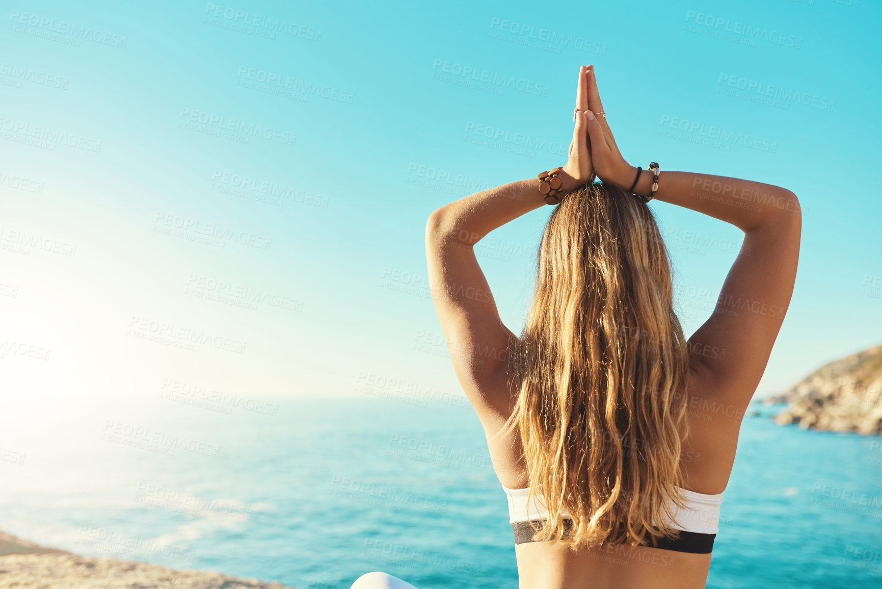 Buy stock photo Rearview shot of a young woman practicing yoga on the beach