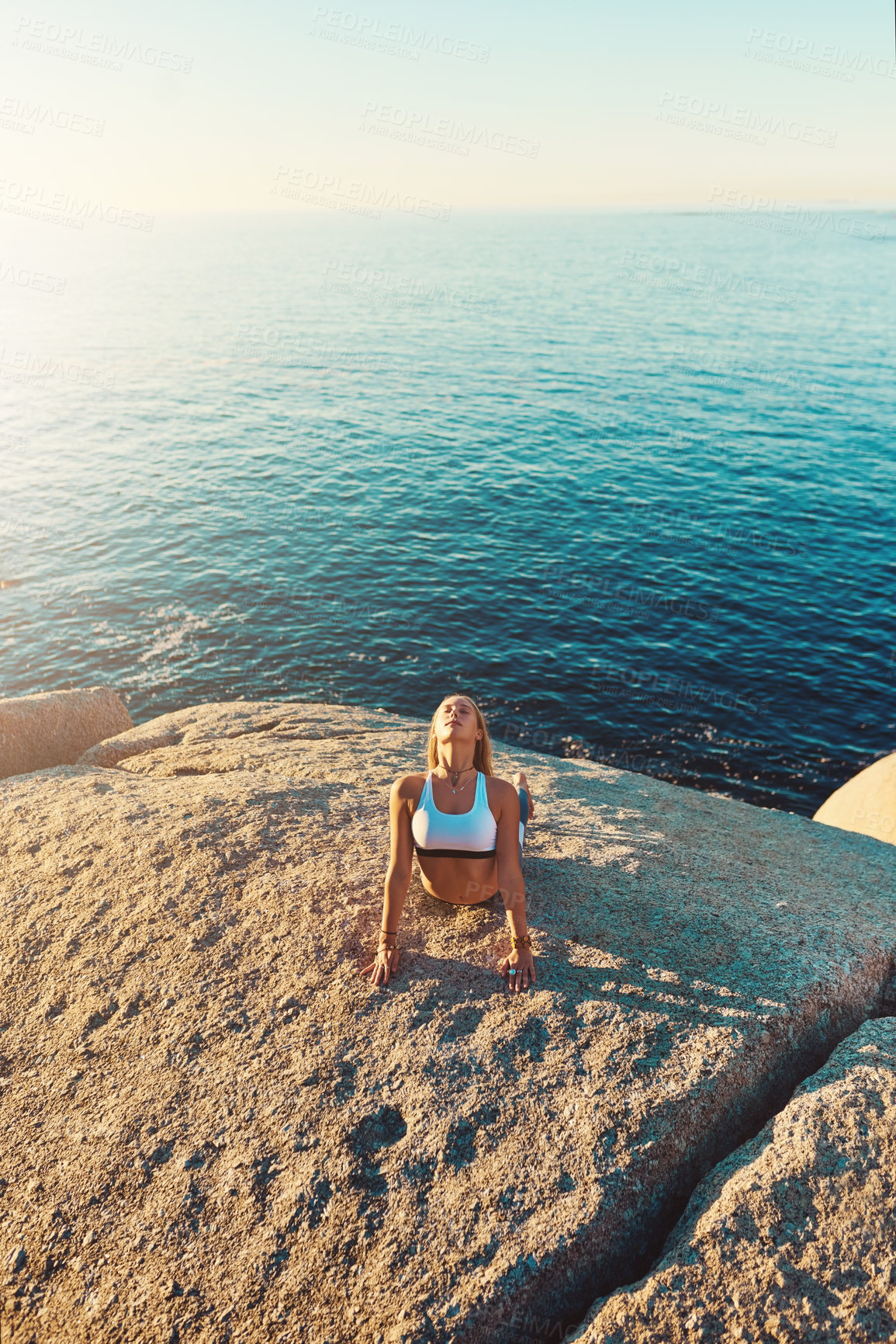 Buy stock photo Shot of an athletic young woman practicing yoga on the beach