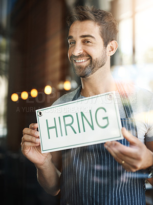 Buy stock photo Man with hiring sign, window with job opportunity advertising, happy waiter or barista in portrait. Small business, recruitment and male owner with onboarding, promo poster for new hire at cafe
