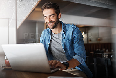 Buy stock photo Shot of a handsome young man using a laptop in a coffee shop